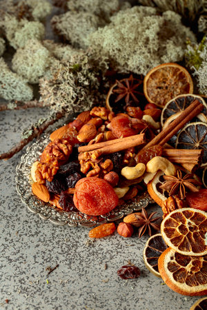 Dried fruits and nuts on a silver try. Still-life with dried citrus, apricots, raisins, various nuts, cinnamon sticks, and anise.の写真素材