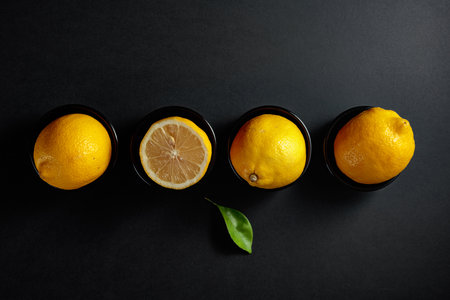 Fresh, juicy lemons in small black bowls on a black background. Top view, copy space.の写真素材