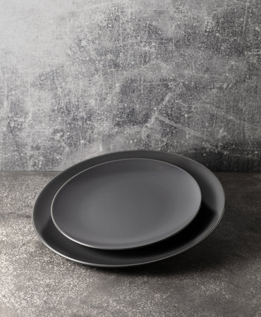 Empty round black plates on a gray stone background with copy space.の写真素材