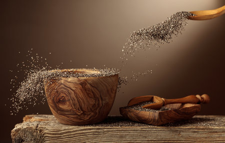 Chia seeds are poured into a wooden bowl. Beige background with copy space.の写真素材