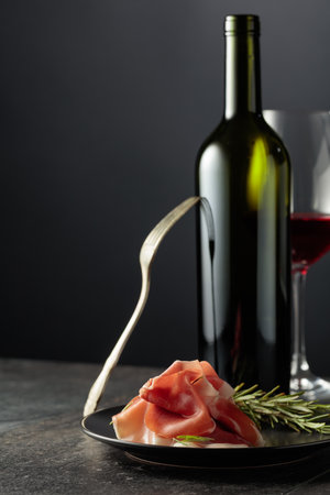 Prosciutto with rosemary and red wine on a black background. Copy space for your text.の写真素材
