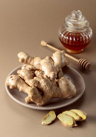 Ginger with honey jar on a beige background, natural medicine concept.