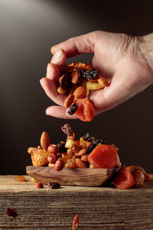 Dried fruits and nuts are poured in a wooden dish.の写真素材