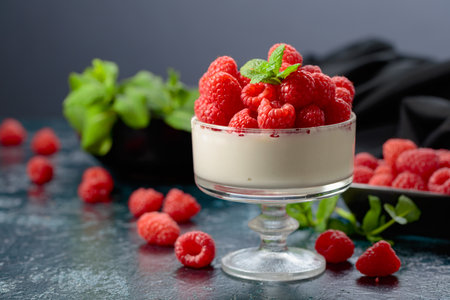 Panna cotta with fresh raspberries in a clear bowl. Berry parfait delight garnished with mint...