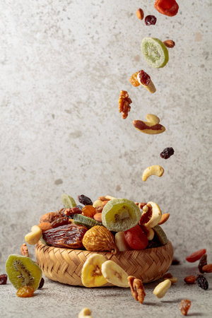 Mix of dried fruits and nuts in motion on a gray stone background. Copy space.の写真素材
