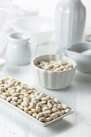 Dried white beans on a white wooden table.の写真素材