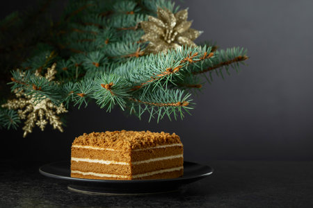 Layered honey cake on a background of Christmas tree. Traditional Christmas pastry. Copy space.