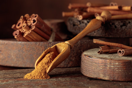 Wooden spoon with cinnamon powder. Cinnamon sticks on a brown vintage background.