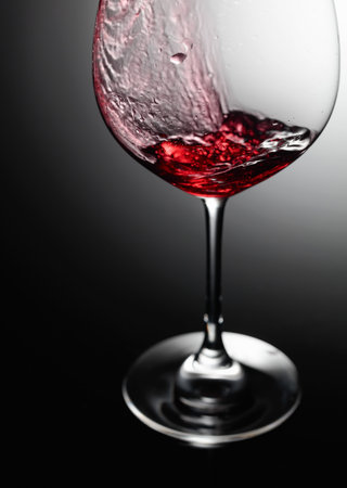 Closeup of red wine pouring on a black background.
