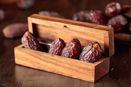 Dates fruits in small wooden box on an old wooden table. Traditional Arabic healthy food.