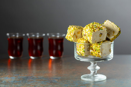 Turkish delights with pistachio and black tea on a dark  background.
