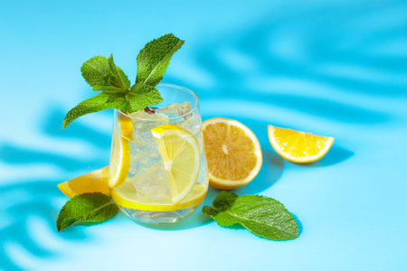 Summer refreshing drink with ice, lemon and mint. Blue background with copy space.