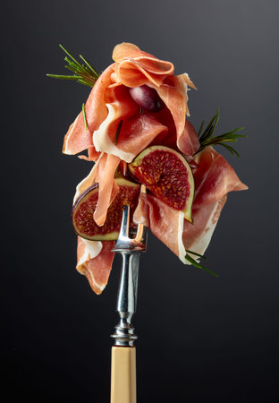 Prosciutto with figs, rosemary, and red olives on a fork. Mediterranean snacks.