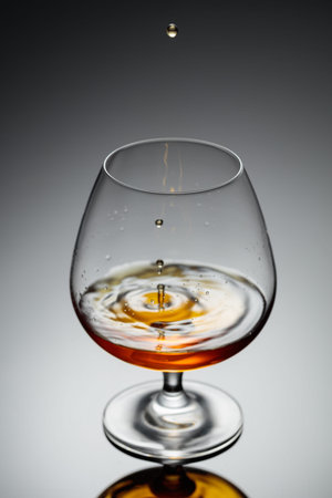 Drop of brandy fall into a glass. A short exposure freezes the movement.