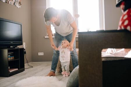 Baby learns to walk dad holds her handsの写真素材