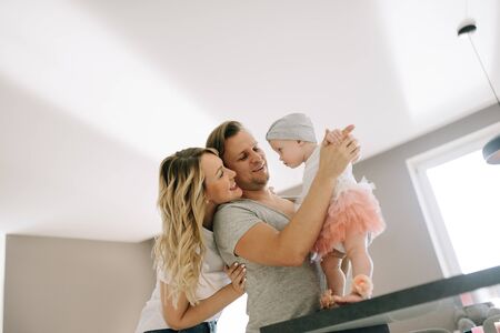 Happy family in bright apartment. Husband and wife playing with their daughterの写真素材