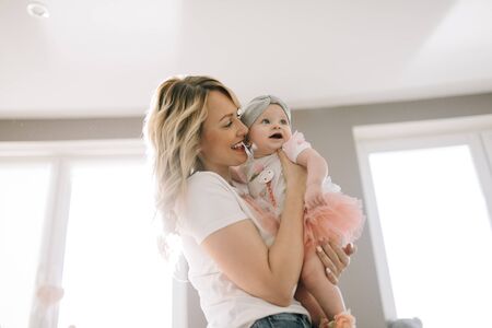 Mom holds baby in her arms in bright room at homeの写真素材