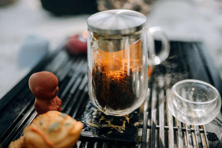 Red tea brewed in a glass teapot. The sun shines through a glass teapot during a tea ceremony. Beautiful atmosphere of the tea ceremony in the morning.の写真素材