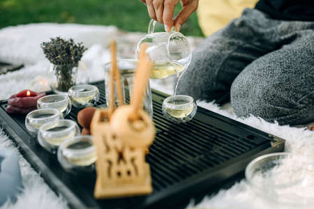 Master of tea ceremony pours green tea into glass cups close up. Tea ceremony in the parkの写真素材