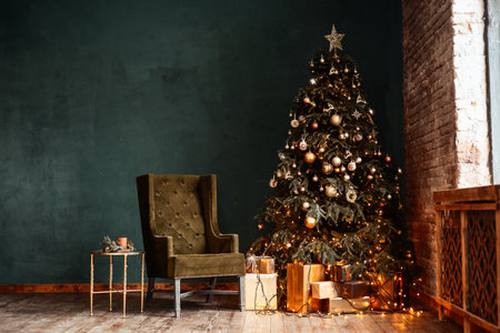 New Year background. Christmas room interior. Light, gifts, candles and hot lighting indoors. An armchair with a table near a Christmas tree with giftsの写真素材