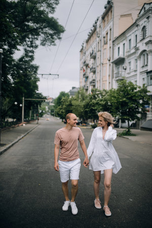 Beautiful young couple in love holding hands walking around the city smiling at each other.の写真素材