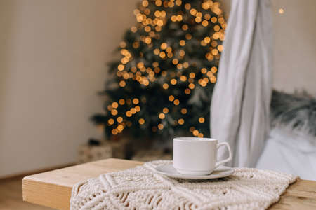 Cozy atmosphere with a cup of coffee on the background of the Christmas treeの写真素材
