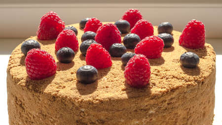 Honey cake decorated with raspberries and blueberries.の写真素材