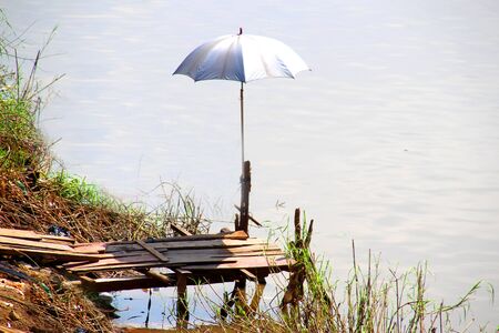 2 A silver sun umbrella stands on a river pierの写真素材