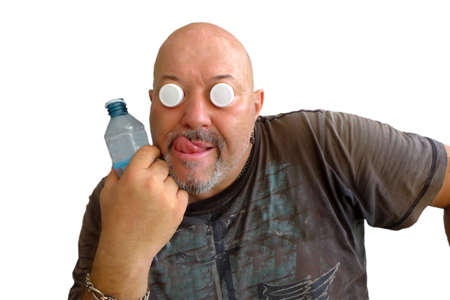 A European man in a dark T-shirt with corks instead of eyes with a bottle and tongueの写真素材