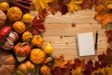 notebook with fallen leaves on wooden background, top viewの写真素材