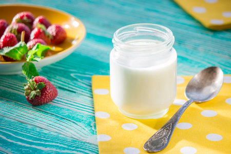 yogurt in a glass jar with strawberries on a blue wooden backgroundの写真素材