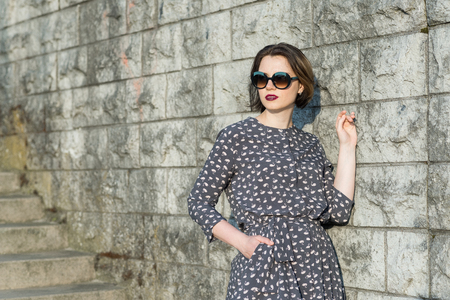 beautiful girl posing in a dress near the wallの写真素材