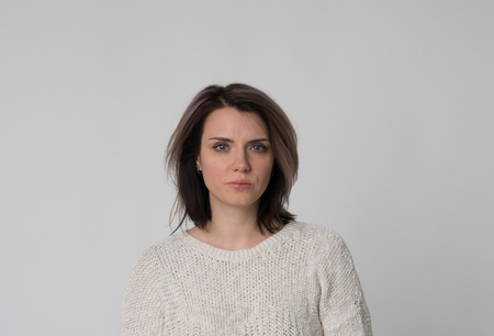 portrait of a young beautiful girl in a white sweater in a studio on a white backgroundの写真素材