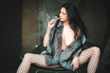 young beautiful girl posing topless in a fur coat in the studioの写真素材