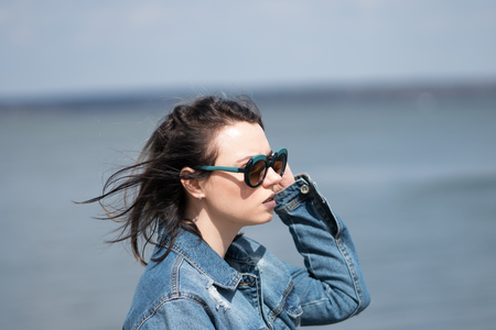 portrait of a young beautiful girl on a sea background in a denim jacketの写真素材