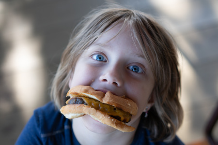 portrait of a girl eating a cheeseburgerの写真素材