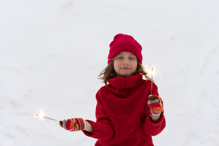 the little girl is standing on the street with sparklersの写真素材
