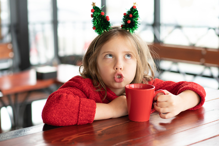 little girl sitting in a cafe at christmasの写真素材