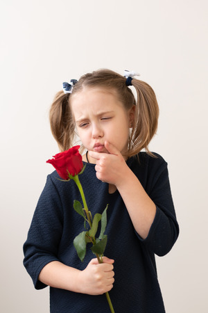 little girl stands with a red roseの写真素材