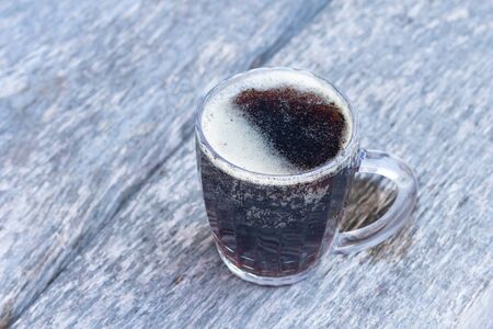 glass mug with dark beer stands on a wooden tableの写真素材