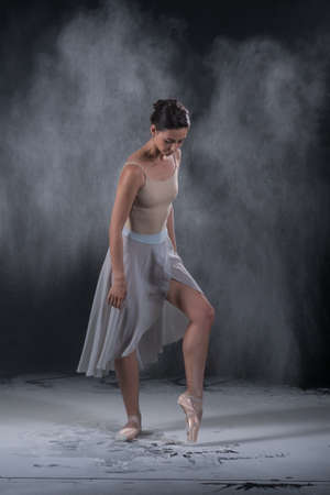 ballerina dancing in the studio with white flour, standing near a black wallの写真素材