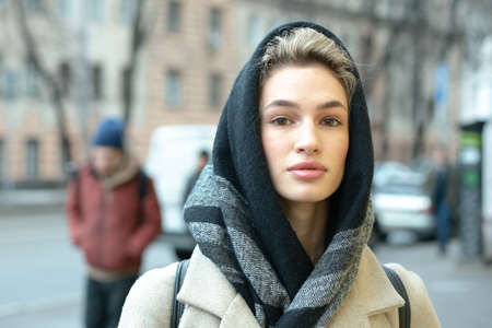 portrait of a young beautiful woman outdoors in spring in a coat and scarfの写真素材