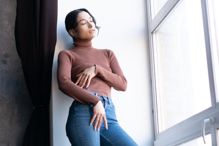 portrait of a young beautiful woman in the studio, stands in blue jeansの写真素材
