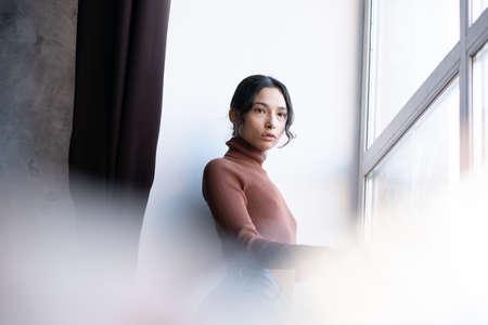 portrait of a young beautiful woman in the studio, stands in blue jeansの写真素材
