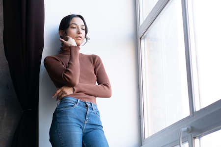 portrait of a young beautiful woman in the studio, stands in blue jeansの写真素材