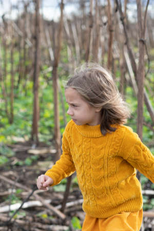 portrait of a little girl in the forest in a yellow sweaterの写真素材