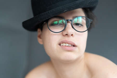 portrait of a young beautiful woman in a black hat and glasses in the studioの写真素材
