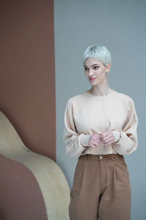 portrait of a young beautiful woman in the studio, standing in a beige sweaterの写真素材