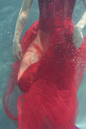 beautiful girl underwater in a red dressの写真素材