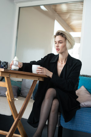 young beautiful woman sitting in a coat at the tableの写真素材